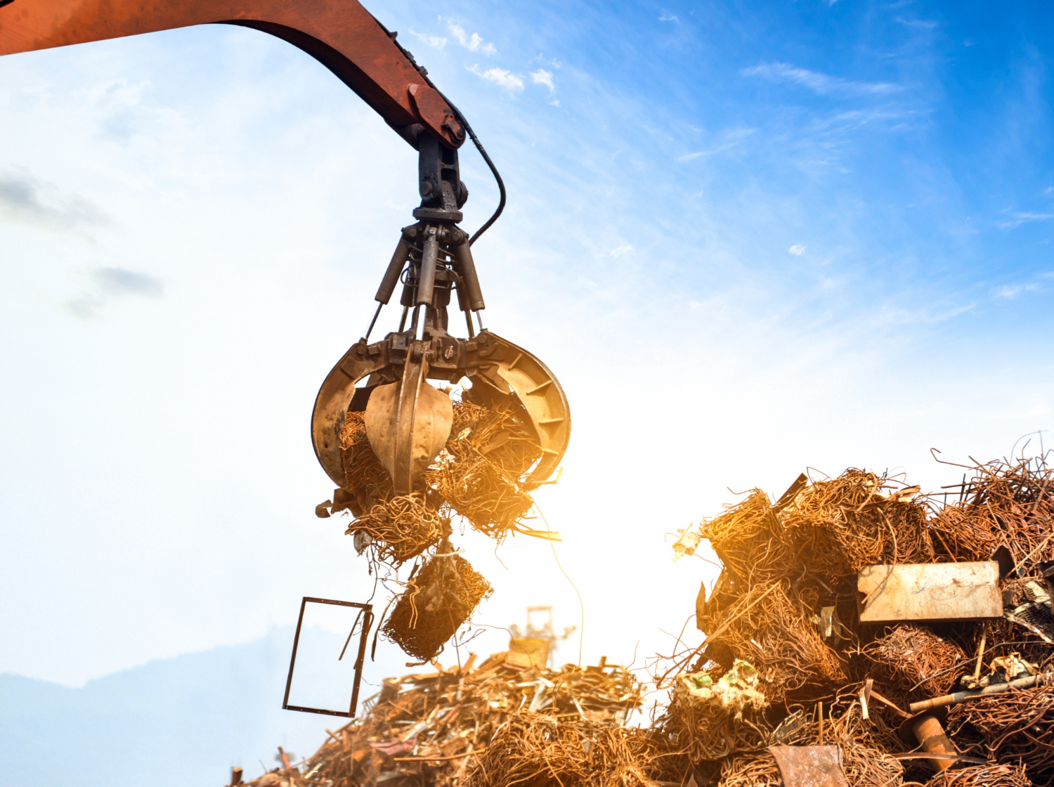 Industrial claw lifting scrap metal at a recycling yard